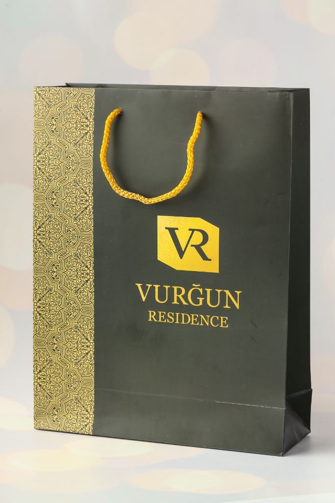 Vurğun Residence gift bag — matte black, gold ornamental side, gold rope handle, VR logo in gold