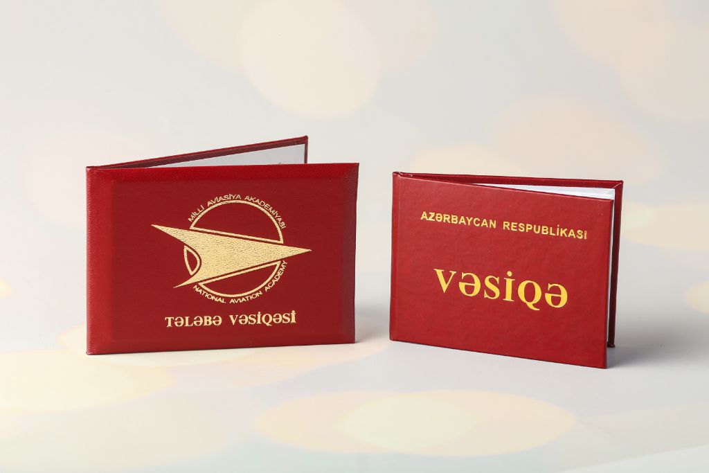 ID booklets of the National Aviation Academy — Student ID (red, gold) and Republic of Azerbaijan ID (red), leather cover