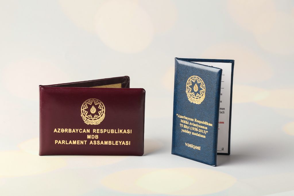 ID booklets of the Republic of Azerbaijan — MIA Parliamentary Assembly (burgundy) and Civil Aviation 75th Anniversary Medal (blue), gold embossing, leather cover