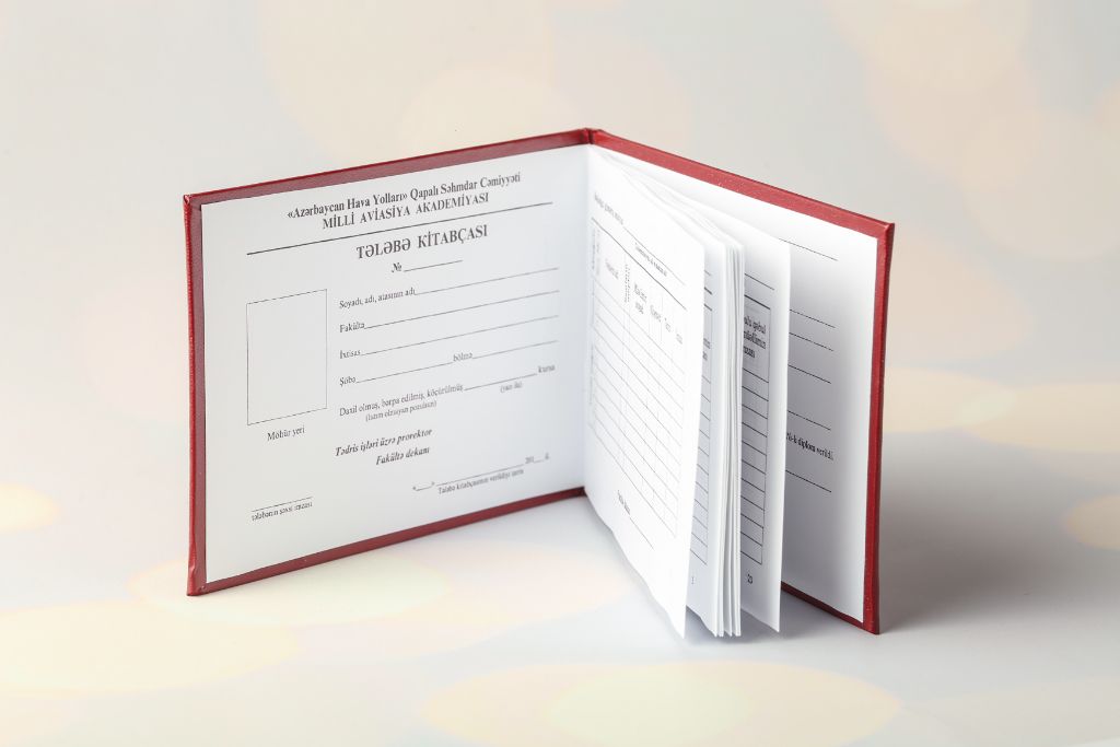 Student booklet of the National Aviation Academy — open, inner pages with grade tables, red leather cover