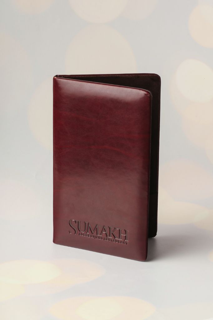 Sumakh menu cover — deep red leather, blind logo embossing
