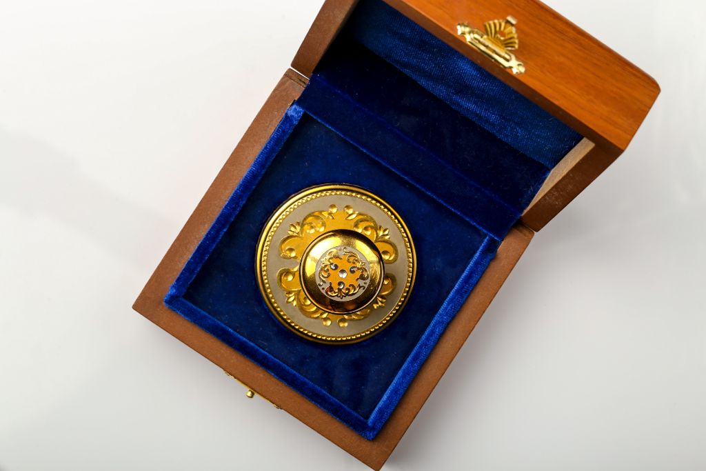 Round VIP stamp with arabesque ornament in wooden casket — front view