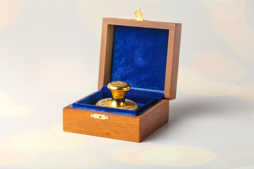 VIP gold round stamp in open wooden casket with blue velvet