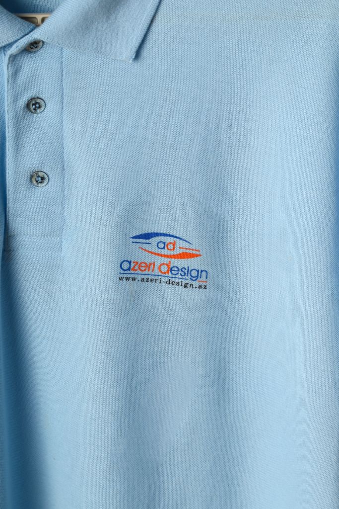 Logo embroidery on chest of sky blue polo — close-up