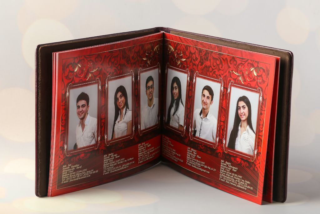 Academic vignette open — spread with graduate photos on red background with gold ornament