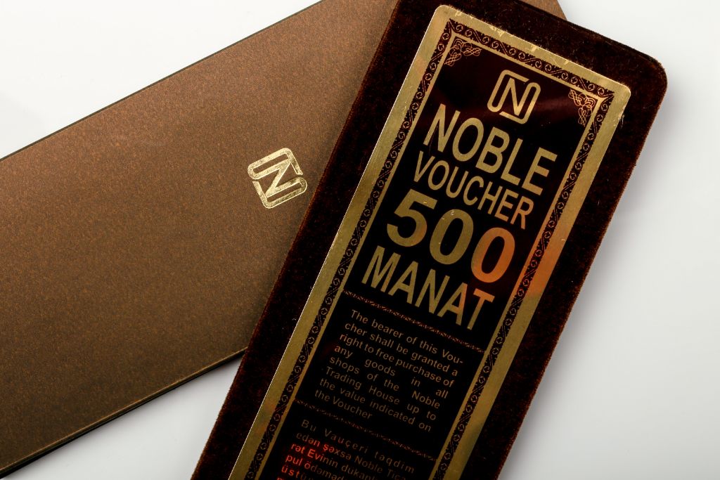 Noble Voucher 500 Manat — close-up of velvet voucher and brown cover with gold logo